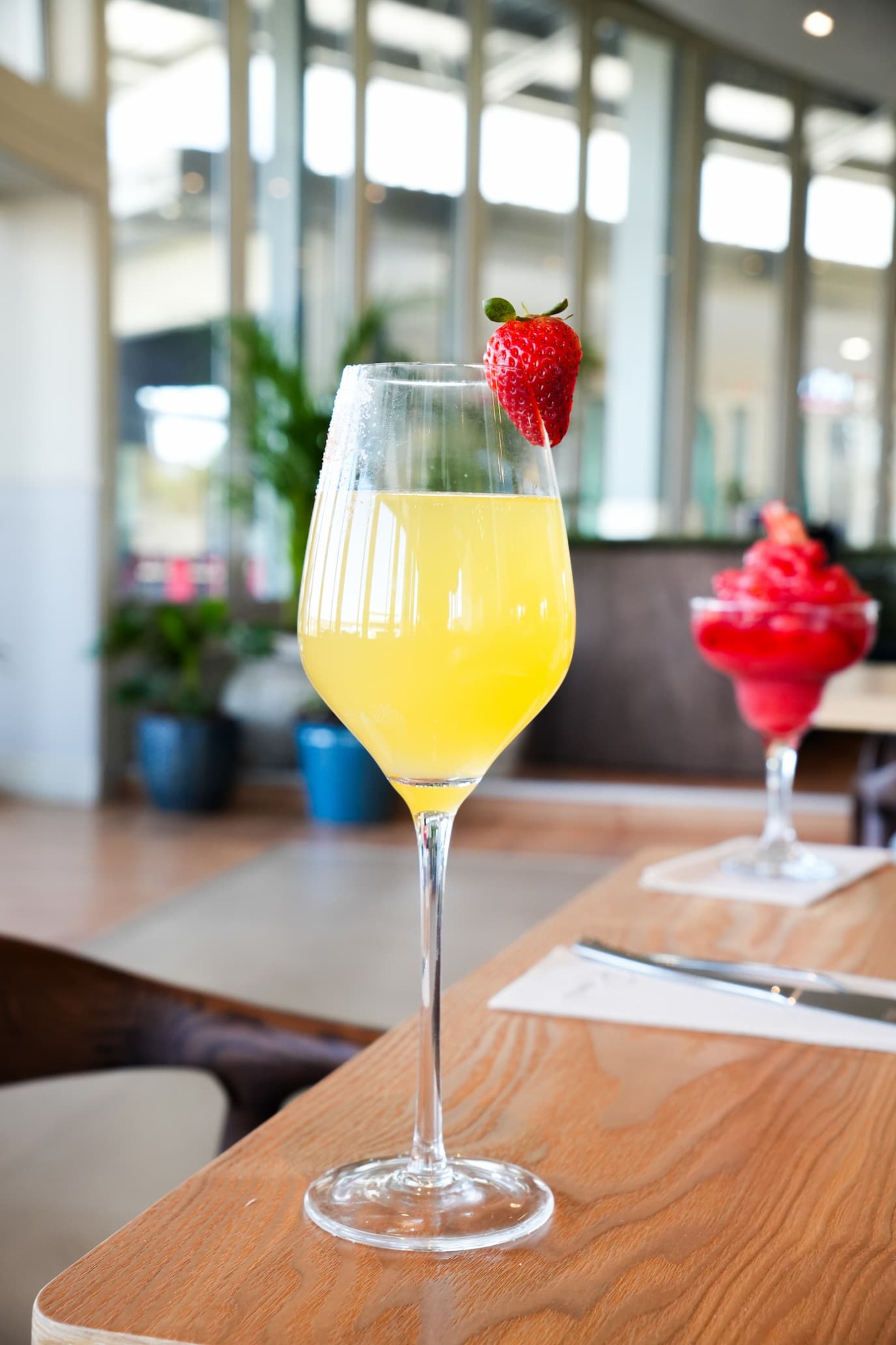 Yellow cocktail with a strawberry garnish